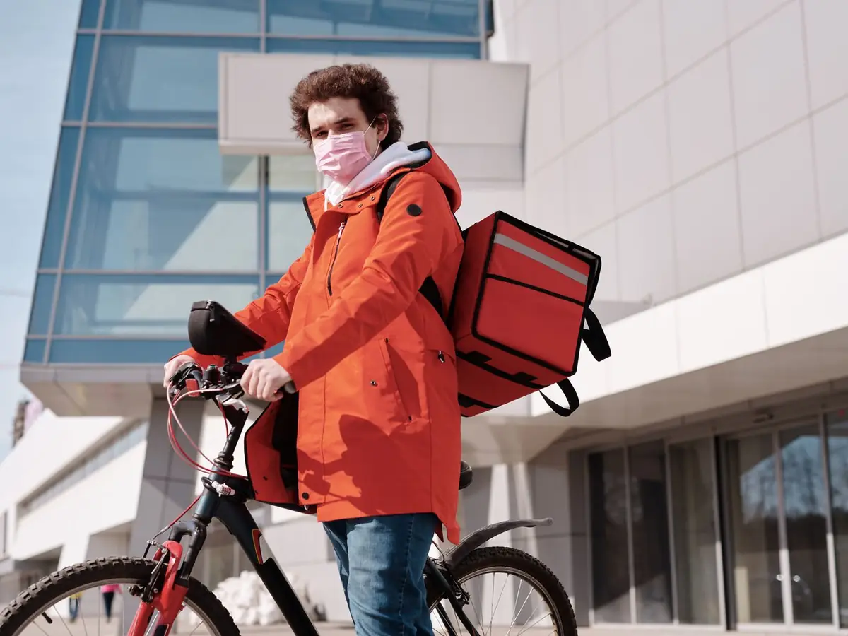 A food delivery courier with a red thermal bag on a bicycle
