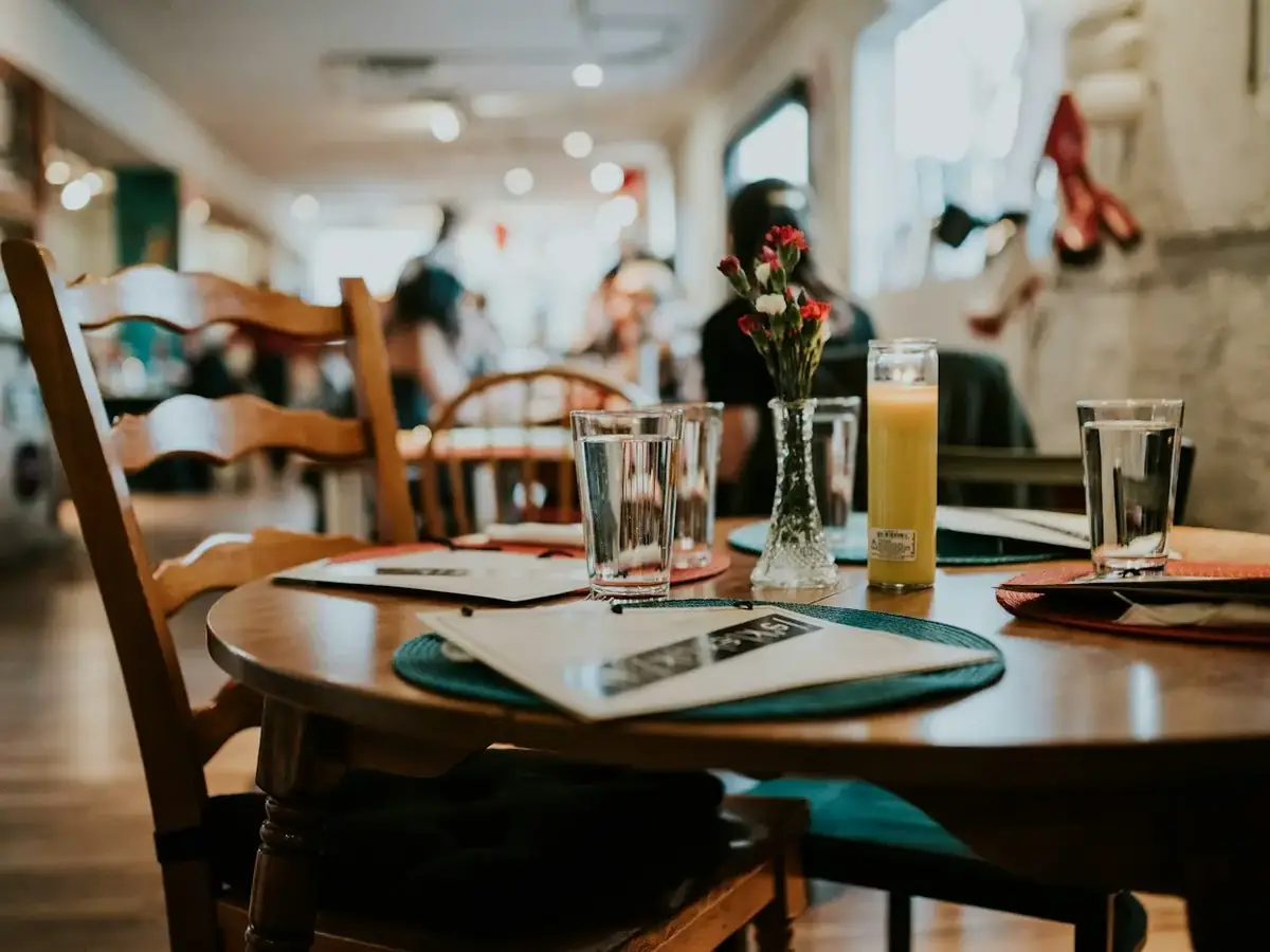 A restaurant dining room with tables set with plates and glasses